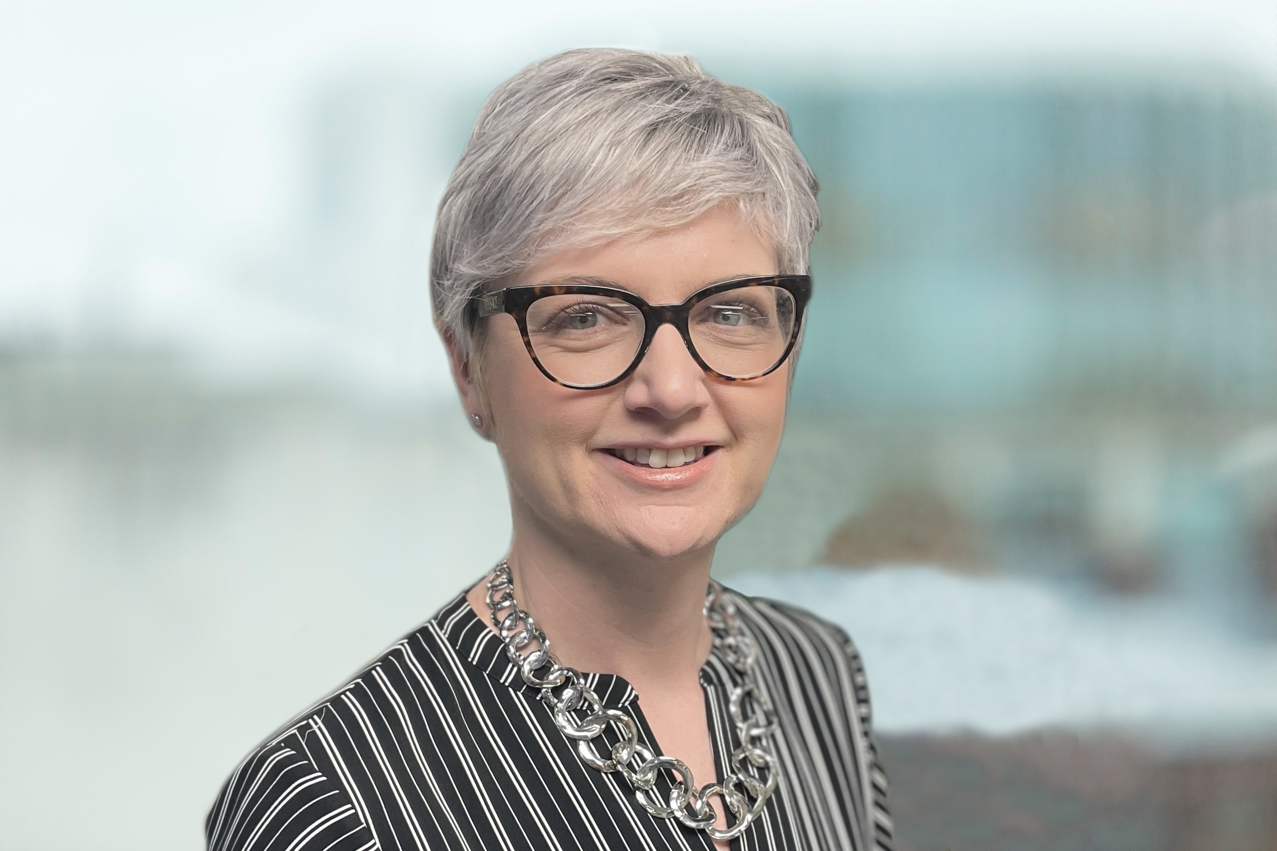 Lisa Commane is pictured with pale skin and light-coloured hair, wearing dark glasses and a navy jacket.