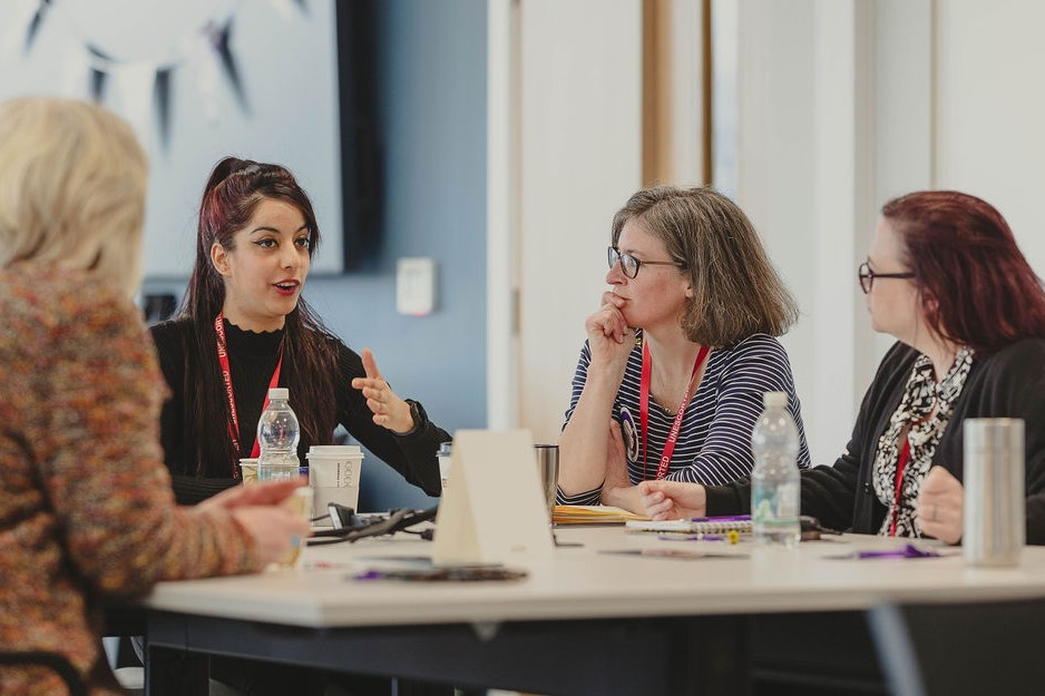 Civil servants sitting around a meeting table having a discussion in a modern office environment.
